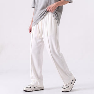 A person wearing loose white drawstring baggy trouser with a gray T-shirt and white sneakers, shown from the chest down against a clean light gray studio background l AH Urban Wear Pk