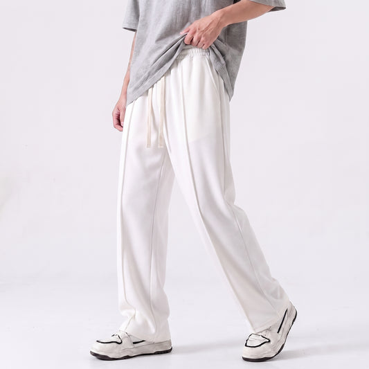 A person wearing loose white drawstring baggy trouser with a gray T-shirt and white sneakers, shown from the chest down against a clean light gray studio background l AH Urban Wear Pk