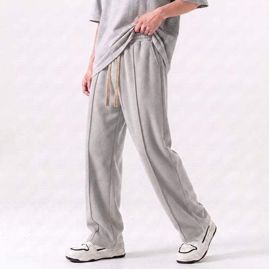 A person wearing light gray wide-leg baggy trouser with a drawstring waist, paired with a matching gray t-shirt and white sneakers, shown from the waist down against a light gray studio background l AH Urban Wear Pk