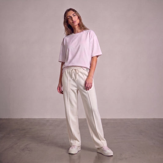 A woman modeling a light pink short-sleeve crewneck t-shirt and off-white drawstring baggy trouser against a neutral studio backdrop l AH Urban Wear Pk